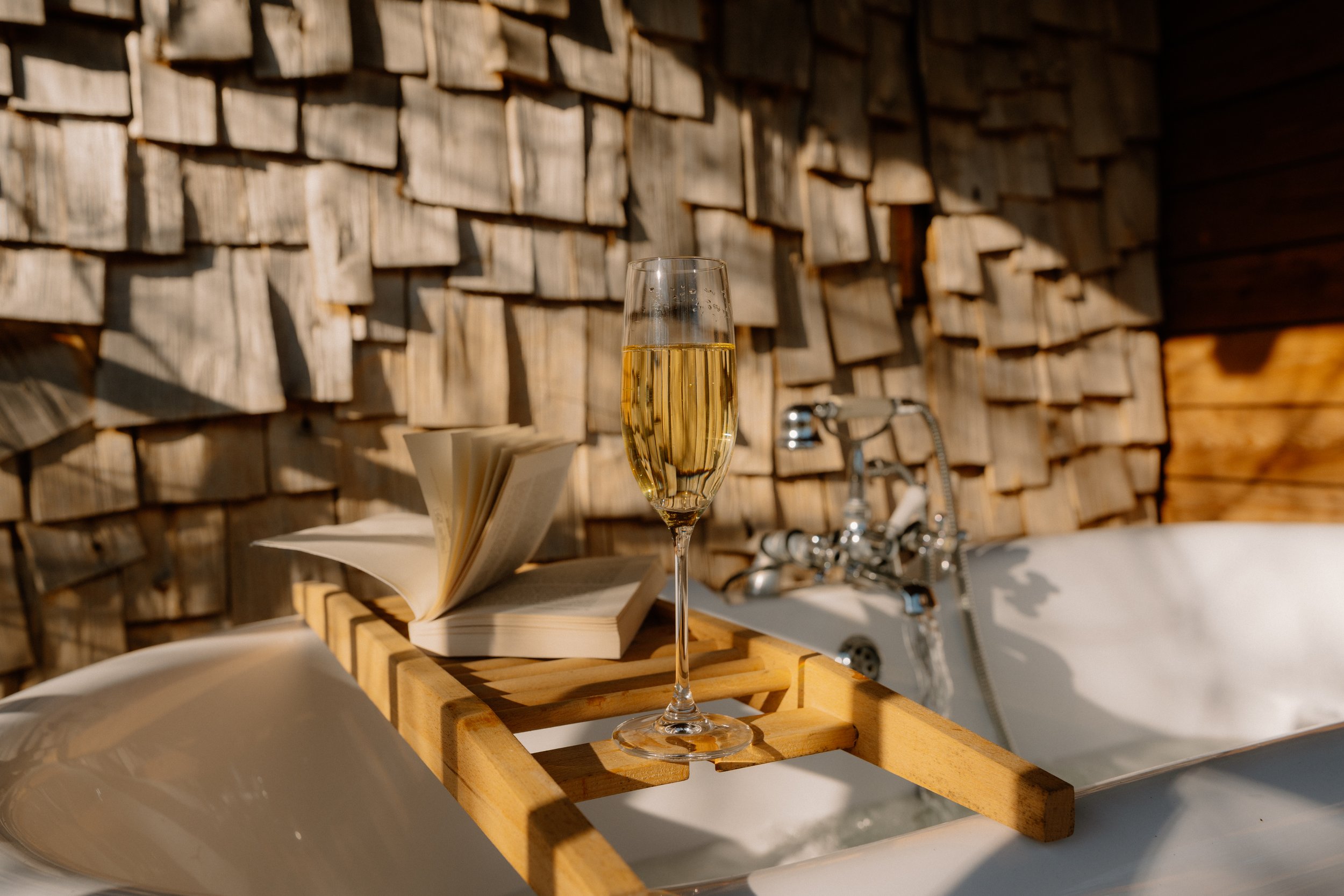 Outdoor bath with book and glass of champagne